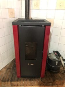 Técnico profesional realizando la limpieza de cenicero y mantenimiento de quemador en una estufa de pellets en Madrid